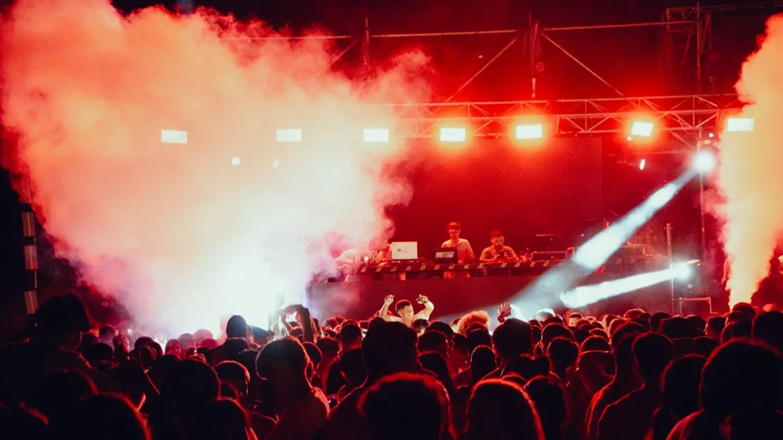 A crowd beneath red concert lighting; stock atmosphere reference
